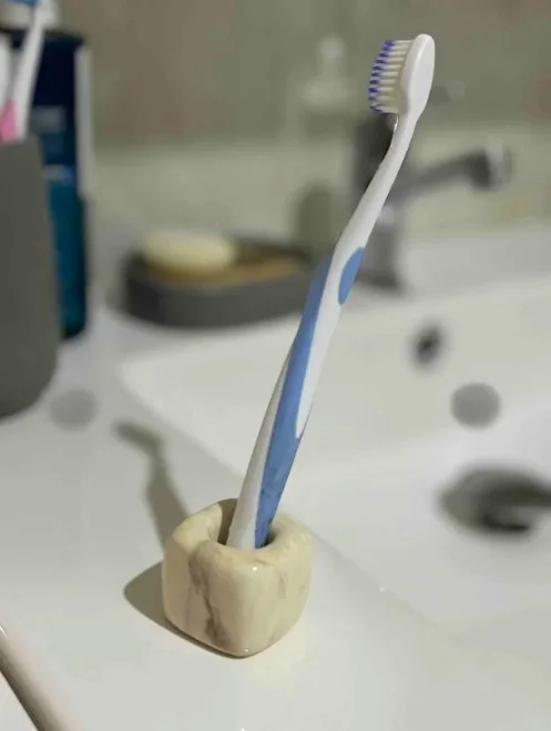 Lavabo kenarında mermer desenli tutacak ve mavi-beyaz diş fırçası